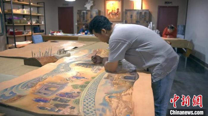 图为蒙古族皮艺非遗传承人贾宏伟正在制作皮雕画，　贾宏伟供图